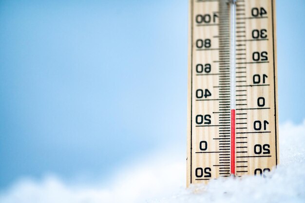 Horário de inverno O termômetro na neve com fundo desfocado mostra baixas temperaturas celsius e farenheit