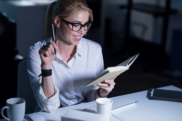 Horário de trabalho agradável. uma secretária sorridente alegre e atraente sentada no escritório fazendo anotações enquanto expressa positividade