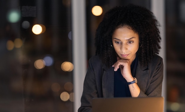 Horas extras noturnas e mulher de negócios em um laptop trabalhando até tarde em um projeto corporativo em seu escritório Escuro profissional e gerente de empresa planejando estratégia de relatório de gerenciamento ou documento no local de trabalho