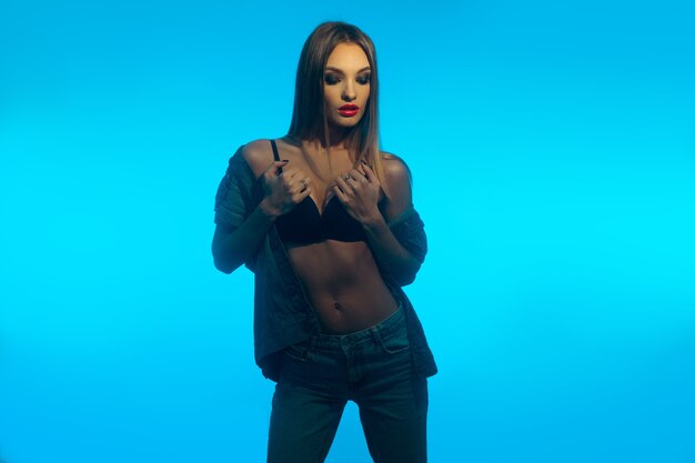 Foto horizontal retrato de dama encantadora con labios rojos en ropa de jeans en azul posando con los ojos cerrados