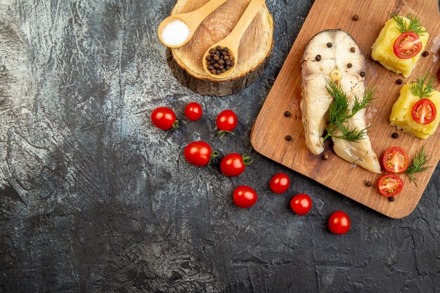 Horizontale Ansicht von gekochtem Fisch-Buchweizenmehl, serviert mit Tomatengrünkäse auf Holzbrettgewürzen auf Eisoberfläche ice