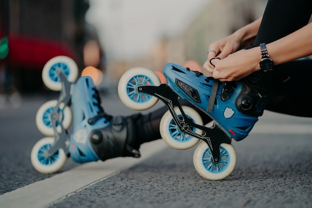 Horizontale Aufnahme einer gesichtslosen Frau, die auf Rollschuhen auf der Straße vor dem städtischen Hintergrund im aktiven Sport posiert. Menschen Hobby Erholung Extremsport aktives Lifestyle-Konzept.