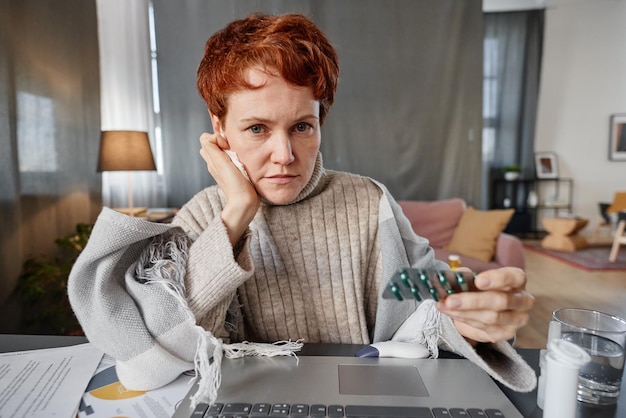 Horizontale Aufnahme einer modernen, reifen kaukasischen Frau, die am Schreibtisch vor einem Laptop sitzt und Arzt a