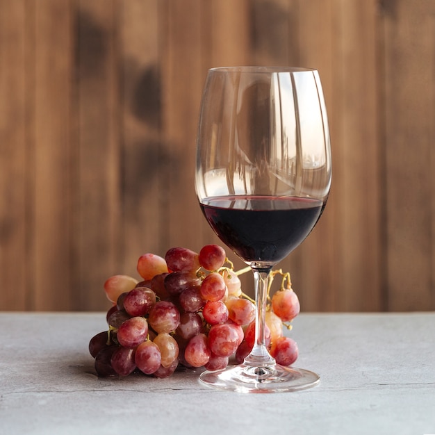 Horizontale Seitenansicht auf einem Glas Rotwein mit Trauben auf dem Tisch