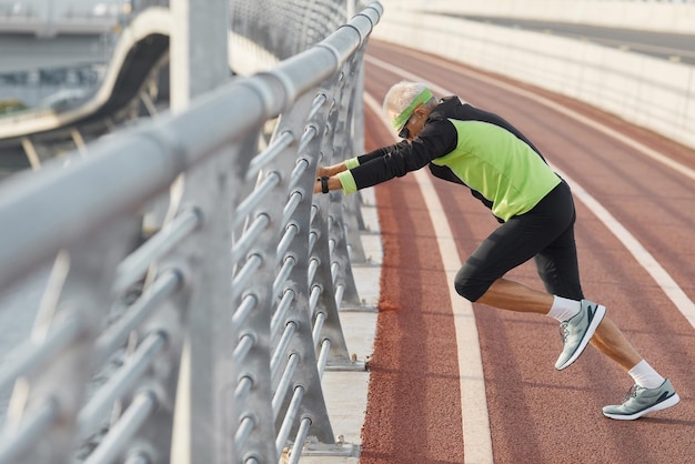 Horizontale Seitenansicht eines modernen älteren Mannes, der einen Trainingsanzug trägt und Aerobic-Übungen macht