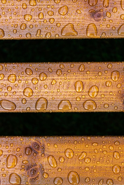 Horizontaler Hintergrund aus lackiertem verbranntem Holz mit glänzenden Wassertropfen aus den regennassen Holzbohlen