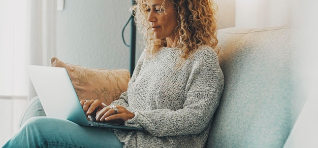 Horizontales Bannerbild mit jungen, reifen Frauen mit Laptop auf dem Sofa sitzend Konzept des Surfens im Internet Menschen Moderne Frauen, die zu Hause am Computer arbeiten, entspannen sich Zeit Dame mit Notebook glücklich