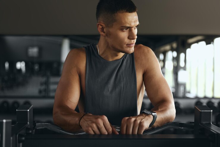 Horizontales Foto von einem muskulösen Fitness-Mann, der sich nach dem Training mit einer schweren ez-Curl-Bar ausruht.