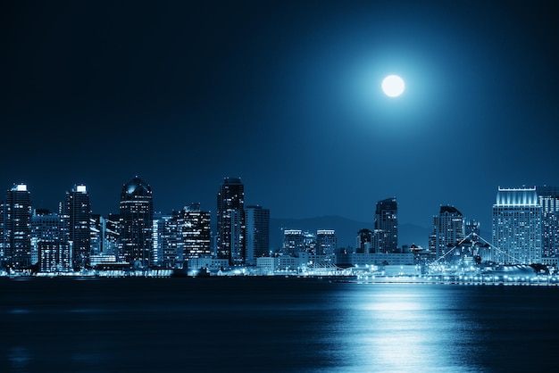 El horizonte del centro de San Diego y la luna llena sobre el agua por la noche en BW