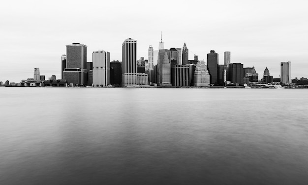 Horizonte de Manhattan en día nublado, rascacielos de Nueva York se refleja en el agua, fotografía en blanco y negro, EE.