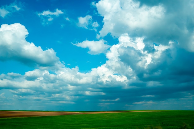 Horizonte con nubes en el cielo azul sobre prado verde