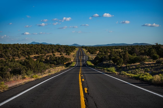 Horizonte panorámico con paisaje de carretera vacía con rocas cielo soleado con nubes y carretera asfaltada en el