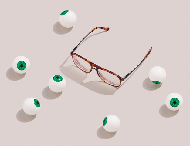 Hornbrille und Augäpfel liegen auf pastellfarbener Oberfläche. Idee Retro-Futurismus und lächerliche Situation.