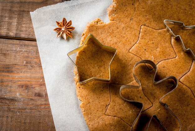 Horneado navideño Masa de jengibre para pan de jengibre Hombres de pan de jengibre Estrellas Árboles de Navidad Rodillo Especias (canela y anís) Harina En la cocina de la casa Mesa de madera