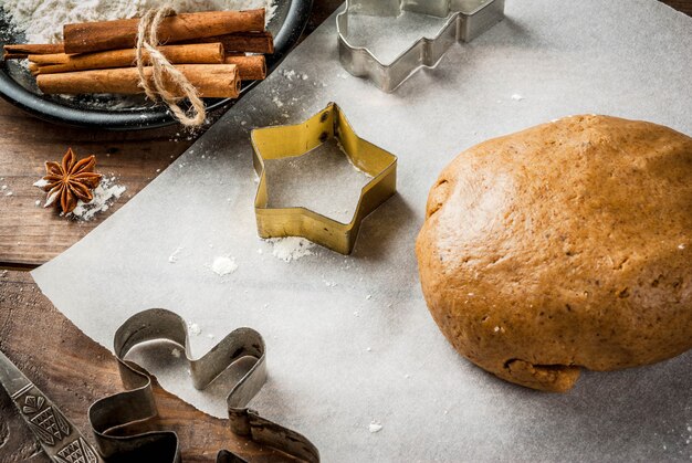 Horneado navideño Masa de jengibre para pan de jengibre Hombres de pan de jengibre Estrellas Árboles de Navidad Rodillo Especias (canela y anís) Harina En la cocina de la casa Mesa de mármol blanco