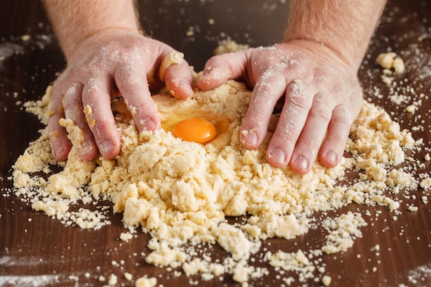 Hornear casero, escena de la cocina que muestra la mezcla de mantequilla, harina, azúcar y semillas de vainilla para hacer galletas de mantequilla, con las manos del hombre.