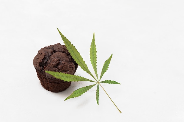 Hornear con concepto de cannabis cupcake brownie con hoja de cannabis en fondo neutro con espacio de copia