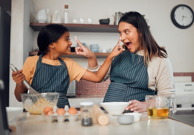 Hornear a la familia y los niños con una madre y una hija aprendiendo a hornear mientras juegan en la cocina Niños divertidos y comida con una niña y una mujer enseñando a una niña a cocinar juntas