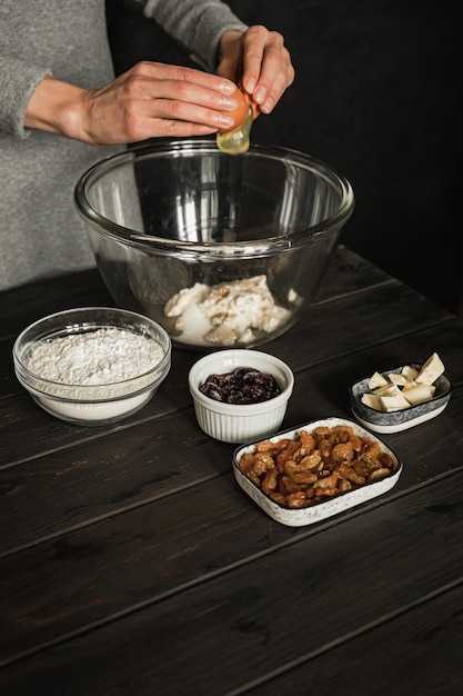 Hornear pan trenzado de requesón dulce con pasas y mermelada. Ingredientes en una mesa de madera. Batir un huevo en un tazón grande. Imagen de estilo de vida.