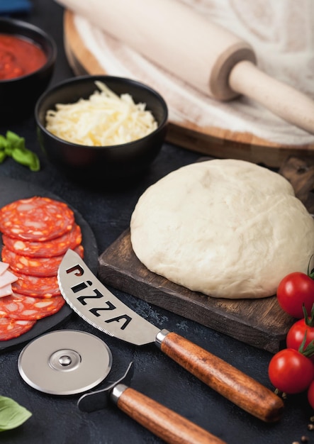 Hornear pizza de pepperoni con chorizo picante de salami de masa cruda con cortador de rueda y