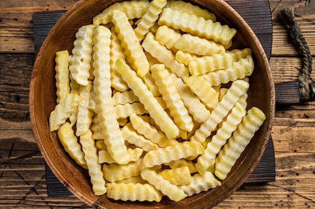 Horno arrugado congelado papas fritas papas en una placa de madera