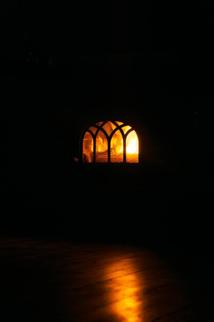 Horno casero con fuego y reflejo en el piso de madera Fondo negro