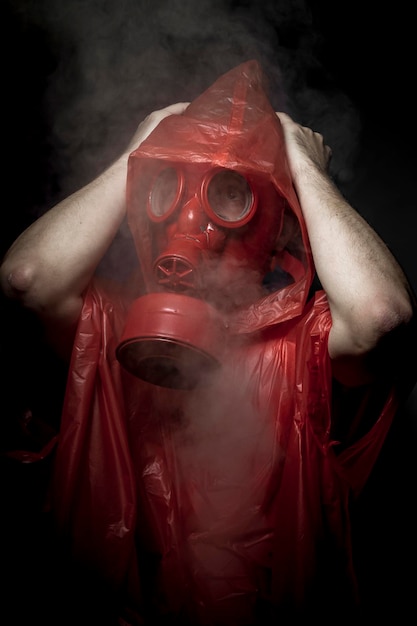 Foto horror, un hombre con una máscara de gas sobre el humo. fondo negro y colores rojos