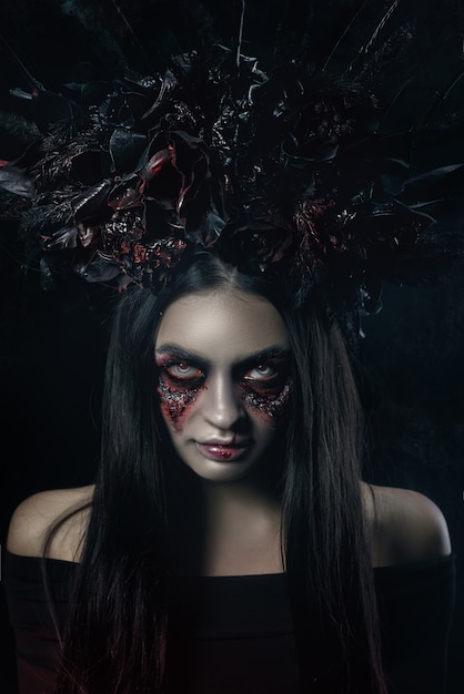 Foto horror terrível retrato de mulher de vampiro de halloween. senhora de bruxa de vampiro de beleza com sangue na boca posando na floresta profunda. projeto de arte da moda. segura uma vela nas mãos e lê maldições