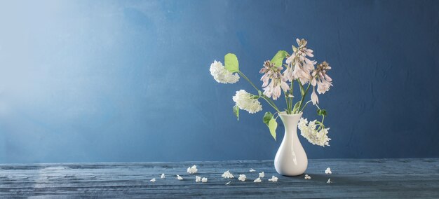 Hortensia blanca en florero sobre mesa de madera