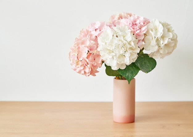 La hortensia rosada hermosa florece en florero en la tabla.