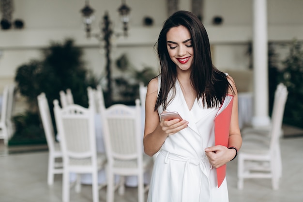 Hostess sorrindo e usando smartphone