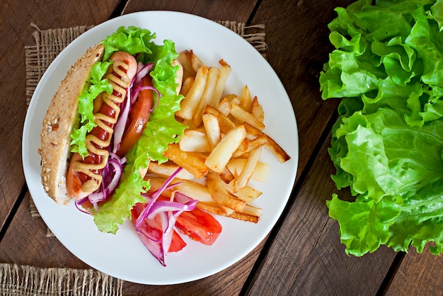 Hot Dog con ketchup mostaza y lechuga en madera