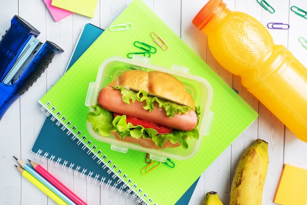 Hot dog con lechuga tomate y salchicha. Cuadernos y papelería. Concepto de escuela Desayuno. Copia espacio
