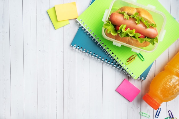 Foto hot dog con lechuga tomate y salchicha. cuadernos y papelería. concepto de escuela desayuno. copia espacio