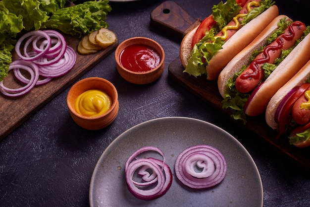 Hot Dog mit Gurken und Salat auf blauem Betonhintergrund.