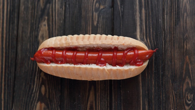 Hot dog con salchicha ahumada sobre fondo de madera oscura.Foto con espacio de copia