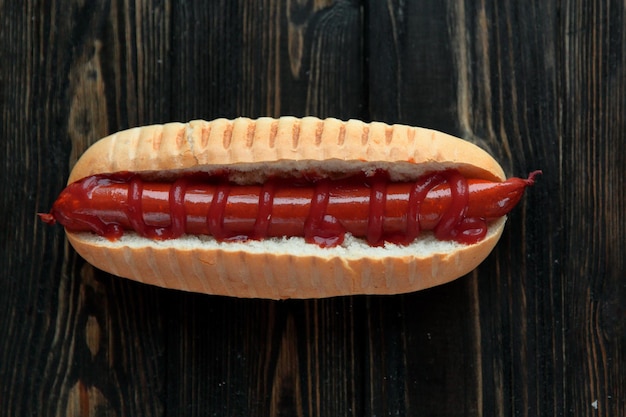 Hot dog con salchicha ahumada sobre fondo de madera oscura.Foto con espacio de copia