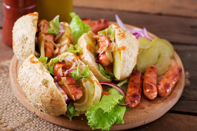 Hot dog - sandwich con pepinillos, cebolla roja y lechuga sobre fondo de madera