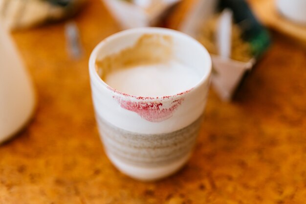 Hot Latte aus Keramikglas mit roter Lippenstiftmarke. Glatter weißer und brauner Schaum.