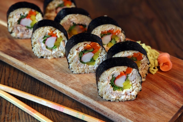 Hot roll set sashimi comida japonesa sobre fondo de madera con limón y palillos