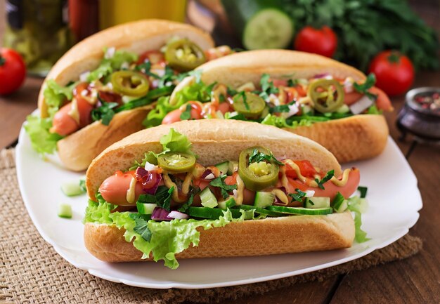 Hotdog mit Jalapeno-Pfeffer, Tomaten, Gurken und Salat auf hölzernem Hintergrund