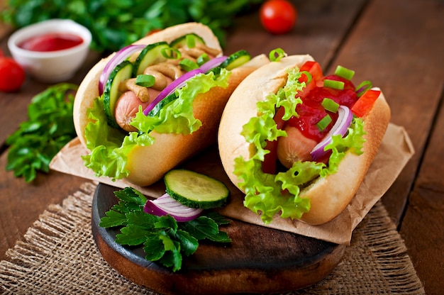 Hotdog mit Ketchup, Senf, Salat und Gemüse auf Holztisch