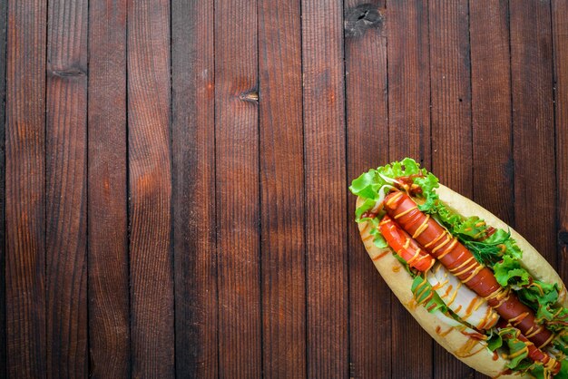 Hotdog mit Kräutern und Gewürzen, Senf und Ketchup auf hölzernem Hintergrund Draufsichtbereich
