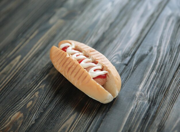 Hotdog mit Soße und Senf auf hölzernem Hintergrundfoto mit Kopienraum