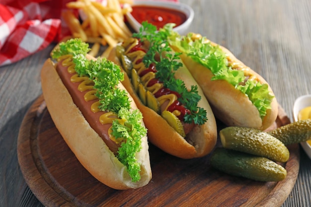 Hotdogs sabrosos con verduras en una mesa de madera de cerca