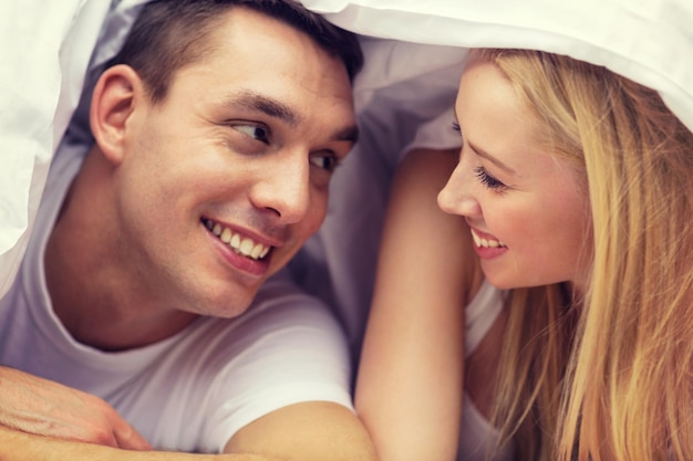 Hotel, Reisen, Beziehungen und Glückskonzept - glückliches Paar im Bett