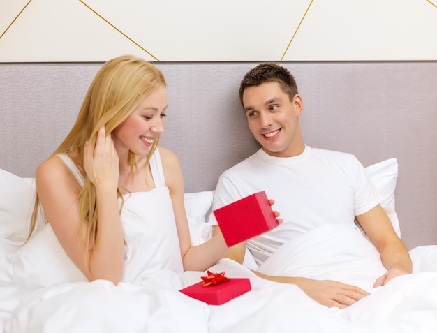 Hotel, Reisen, Beziehungen, Urlaub und Glückskonzept - Mann, der Frau kleine rote Geschenkbox gibt