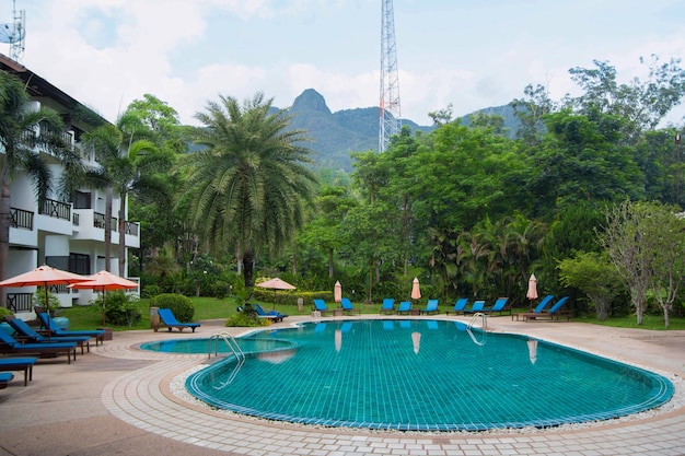 Hotel tailandés desierto con una piscina, palmeras y hamacas en un día soleado Vista frontal