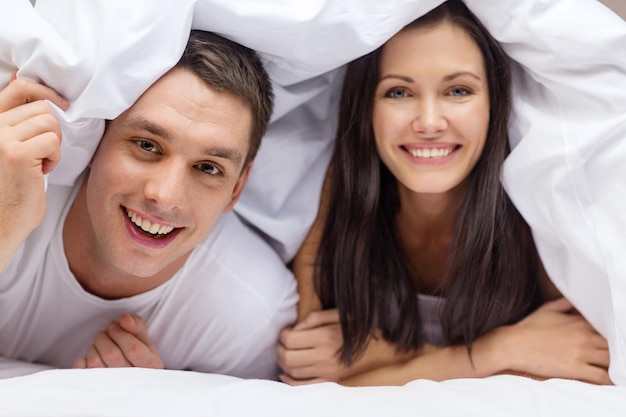 hotel, viagens, relacionamentos e conceito de felicidade - casal feliz na cama