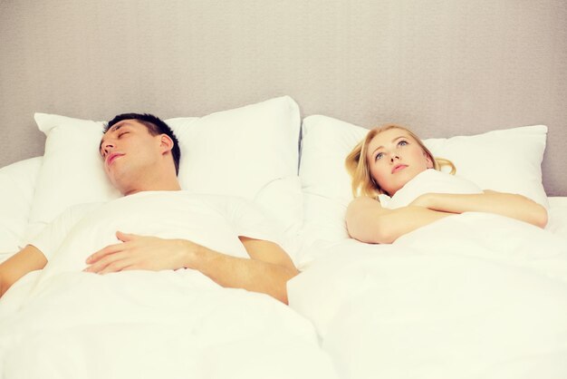 hotel, viajes, relaciones y problemas con el concepto de sueño: pareja familiar en la cama, mujer con insomnio